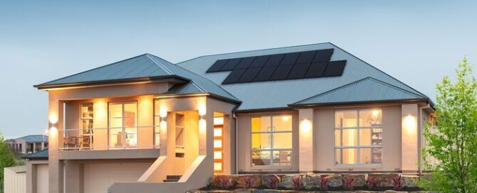Beautiful two-story home shown with interior lights on during the evening time. Solar panels installed on roof.
