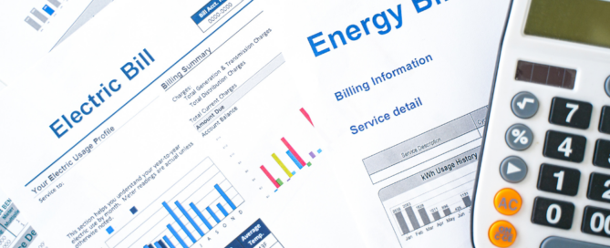 A close-up of energy bills and an electric bill with a calculator placed on top, featuring graphs and data charts.